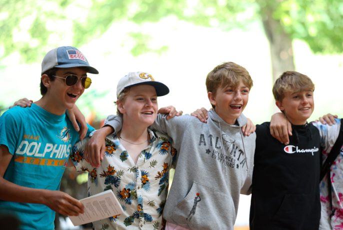 four campers laughing in morning assembly
