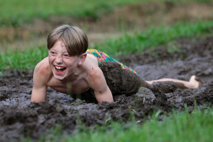 camper laughing while going through the mud pit